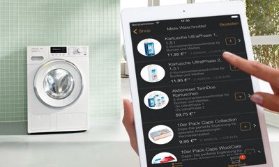 Moderne silberne Heißluftfritteuse mit Digitaldisplay, umgeben von Kartoffeln, Küchenutensilien und Gewürzmühlen.